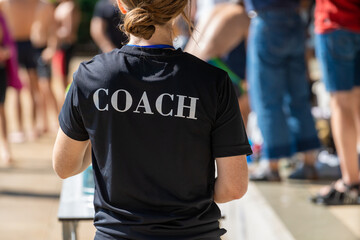 Back view of swimming coaches, wearing COACH shirt
