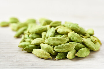 heap cardamom pods on a white wooden table, selective focus.