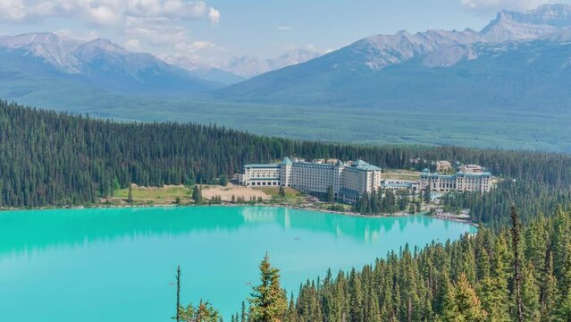 4K time-lapse UHD video of beautiful panoramic view of Lake Louise, a glacier mountain lake in Banff National Park, and Fairmont Chateau Hotel from a side view on a sunny summer day, Alberta, Canada
