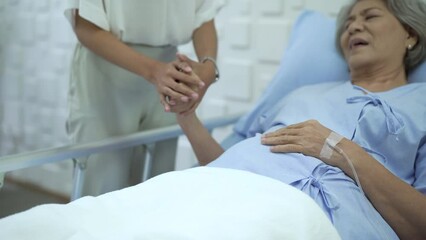 Young woman embracing and encouraging her mother while recovery in hospital ward.