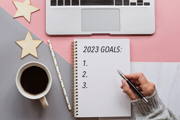 flat lay of desktop with hand writing in notepads goals and plans. 2023 New Year's goal, action text on notepad with office accessories. Business motivation, inspiration concept. Mockup with copy