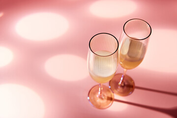 Glasses of champagne on pink background