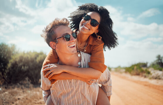 Love, happy and couple piggy back on road path in Arizona desert in USA for romantic getaway. Interracial people dating smile while enjoying summer romance on travel holiday adventure together.