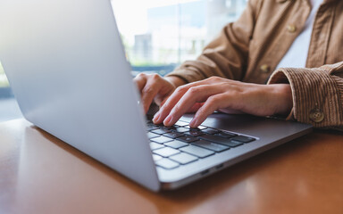 Closeup image of hands working and typing on laptop computer keyboard