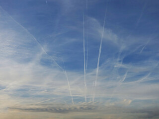 Fototapeta na wymiar Airplanes trails and lines on the blue cloudy sky