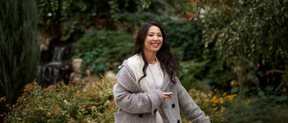 Portrait of pretty asian kazakh brunette woman with charming smile walking along outdoors
