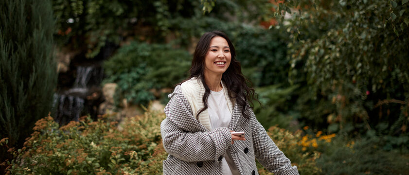 Portrait of pretty asian kazakh brunette woman with charming smile walking along outdoors
