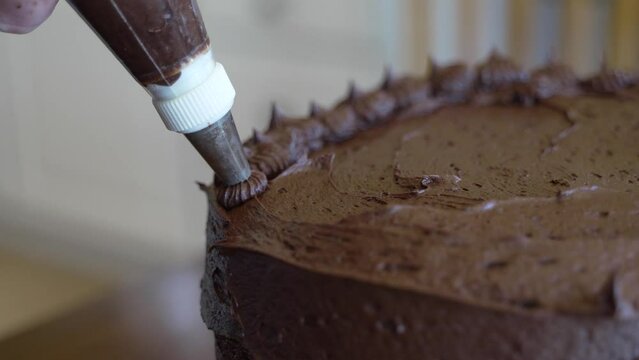 Decorating a cake with an icing bag and tip - isolated close up CHOCOLATE CAKE SERIES