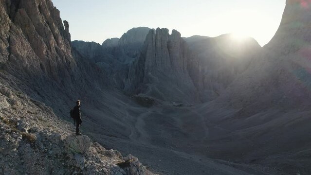 Fly over shot of a person in top of the mountain at sunrise in Torri Vajolet, Dolomites