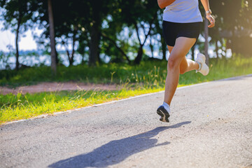 Crop image of silhouette of young woman running sprinting on road. Fit runner fitness runner during...