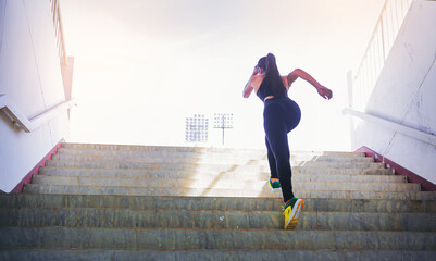 Young woman running sprinting up stairs at stadium. Fit runner fitness runner during outdoor workout. Selected focus