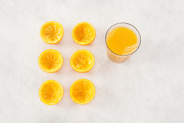 Jus d'orange fraîchement pressé. Oranges coupés exprimés et verre plein. Vue de dessus, fond texturé blanc. Original et tendance.