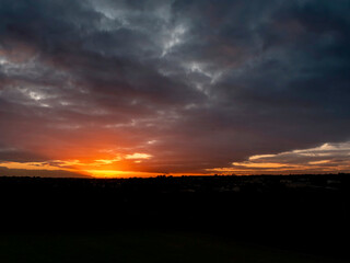 Dramatic sunset nature scene. Warm orange color sky with sun rays and flare. Stunning nature scene at dusk.