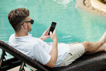 Man using smartphone at outdoor pool