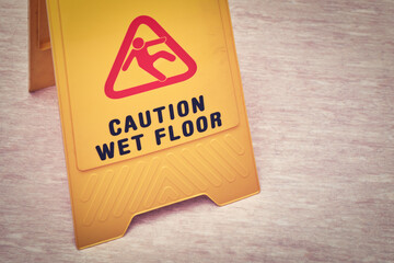 Falls and injuries on the wet floor. The sign on the plate with the text - caution wet floor