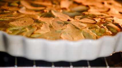 Apple pie is cooked in the oven on a dish. The process of baking an apple pie in a home kitchen