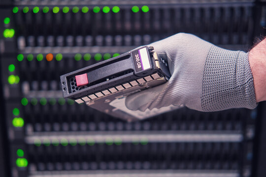 A hard disk for a raid in the hands of a man at a data storage server, close-up