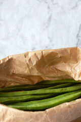 Fototapeta na wymiar Raw green beans in a brown paper bag. Eco friendly recycling packaging concept