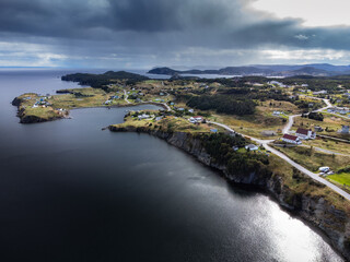 Aerial Newfoundland East Coast community with homes on high cliffs near Port Rexton and the distant Skerwink hiking trail.