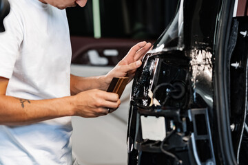 Close up of car wrapping specialist putting protective film on a car in detailing service