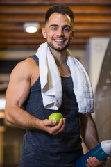 man in gym holding apple and water bottle