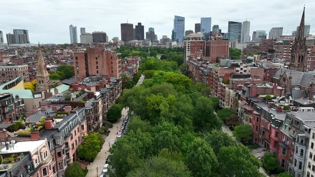 Aerial Dolly Forward Over Green Park Trees In Suburb Of Boston, MA. Inner City Boston Skyline And Cityscape In Background. Tall Houses And Homes Line Green Space In City. Historical Housing District.