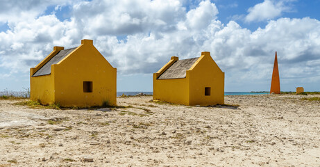 Orange obelisk with yellow slave huts on the old salt production plantation, Bonaire