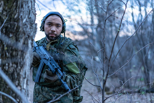 soldier in the forest. a man in military uniform in the branches of trees, in an ambush with a weapon, rifle or machine gun. military actions. airball game
