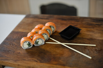 sushi roll with salmon, avocado, cucumber and wasabi on wooden board