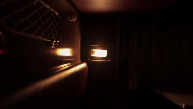 Inside compartment of corridor coach of railway passenger train at night. Light from luminaire is lit inside carriage. City lapms outside window. Empty russian railroad wagon. Travel tourism. Nobody