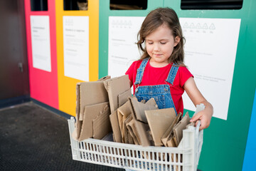 Sustainble lifestyle concept, Girls recycling cardboard in paper bank. Children putting papers in...