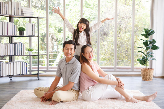 Real estate and mortgage concept : Family with child having fun in new home. Joyful first-time buyers in living room. Real estate, residential mortgage, moving into dream house.