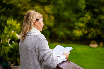 Beautiful woman standing on terrace reading book  contemplating nature