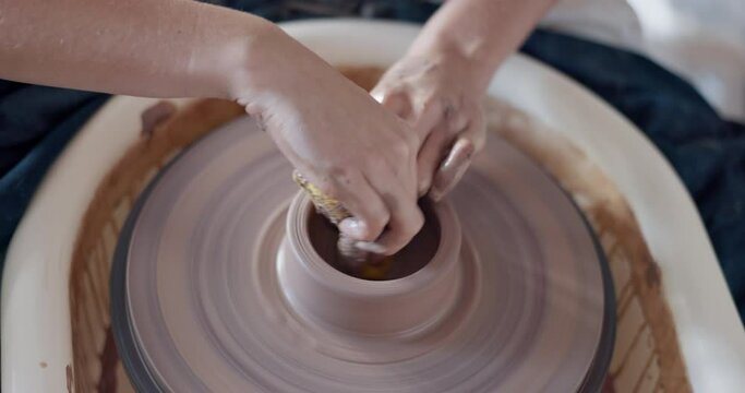 Pottery, art and hands on a potter wheel with artist spinning clay in creative class, workshop or studio. Creativity, handicraft and closeup of a sculptor working on ceramic design, craft or creation