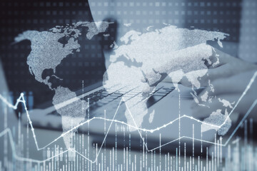 businessman hands using laptop keyboard with abstract glowing map hologram on blurry office desktop background.