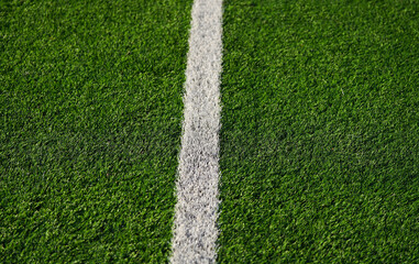 Fototapeta premium Close up detail field of the artificial grass from a brand new soccer field, view with the white marking line.