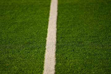 Close up detail field of the artificial grass from a brand new soccer field, view with the white marking line.