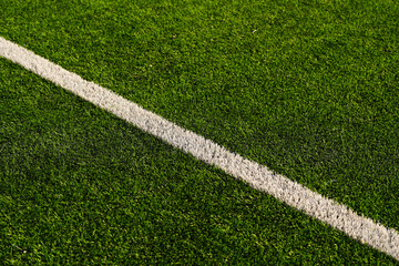 Close up detail field of the artificial grass from a brand new soccer field, view with the white marking line.