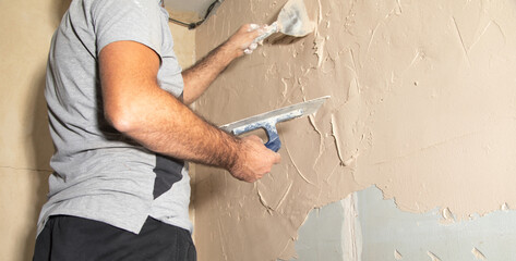 Man is applying putty on a wall. Renovating house