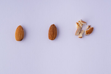 Raw almonds with smashed almonds on a white background