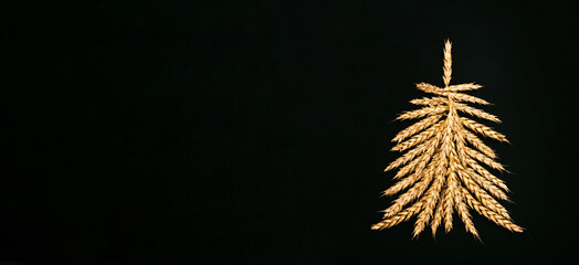 Creative Christmas tree made of wheat ears on a black background.Christmas and New Year flat...