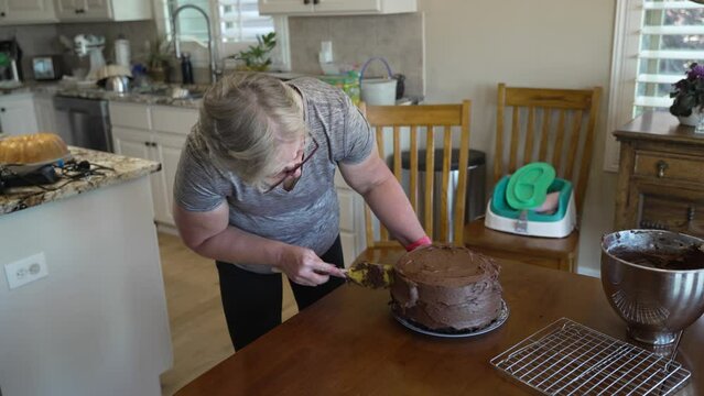 Senior woman homemaker icing a cake - CHOCOLATE CAKE SERIES