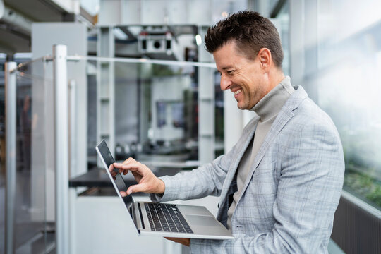 Happy Businessman Touching Laptop Screen In Industry