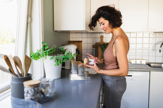 Woman labeling jar standing at kitchen counter