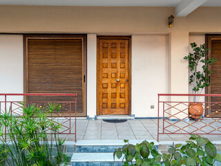 A contemporary house entrance, with wooden door and window shutters. Athens, Greece.