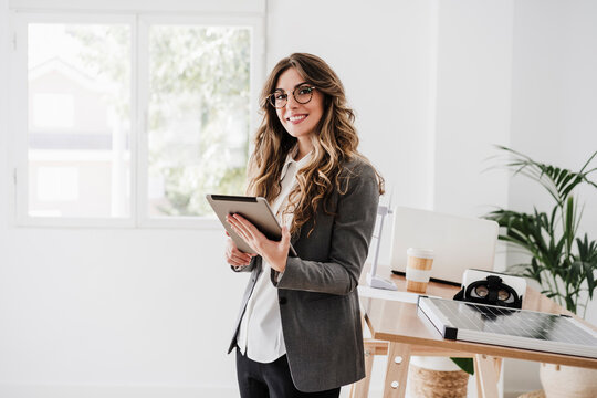 Young businesswoman using tablet standing in modern office
