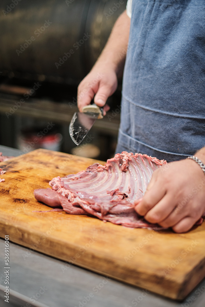 Wall mural The butcher cleans the lamb ribs. Preparing meat for smoking or barbecue