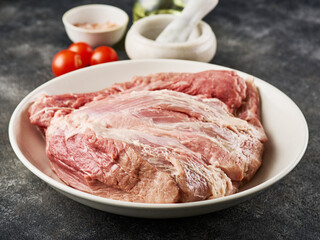 Fresh raw pork shoulder with ingredients for marinade: pepper, salt, olive oil, rosemary, garlic, close-up