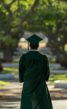 graduate in cap and gown with trees on the side