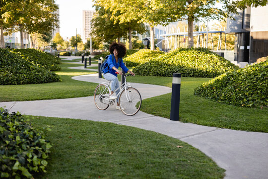 Smiling woman with bicycle on footpath in park